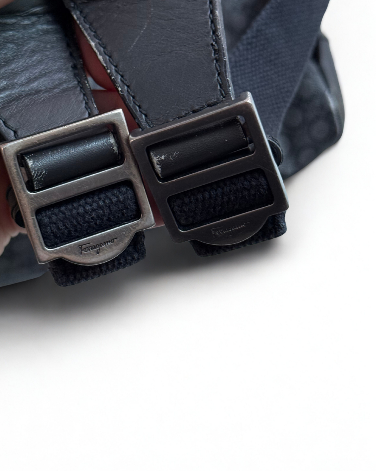Close-up of  Salvatore Ferragamo leather backpack silver buckles on a white background