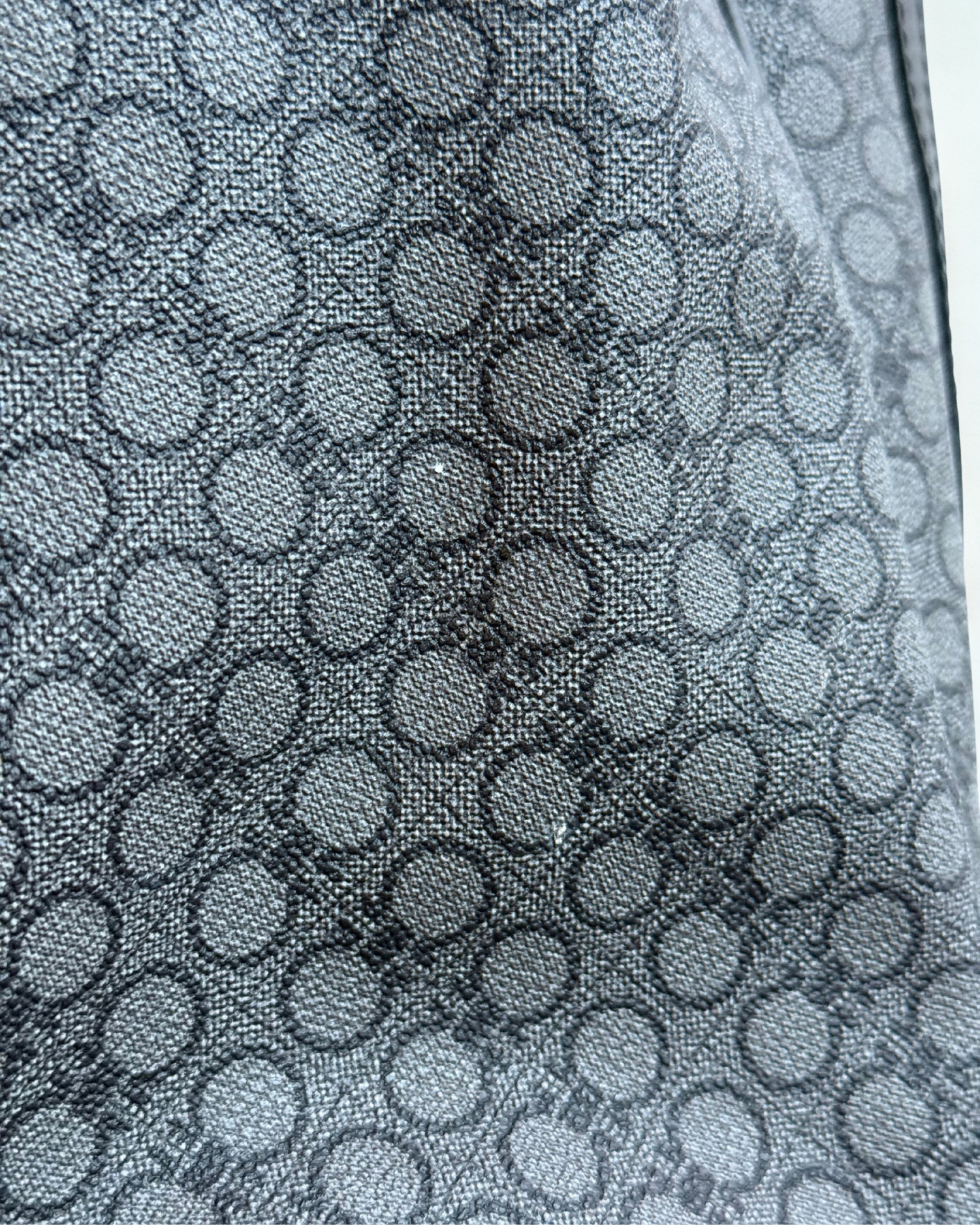 Close-up of a small pre-loved spot on textured fabric with circular patterns in gray tone