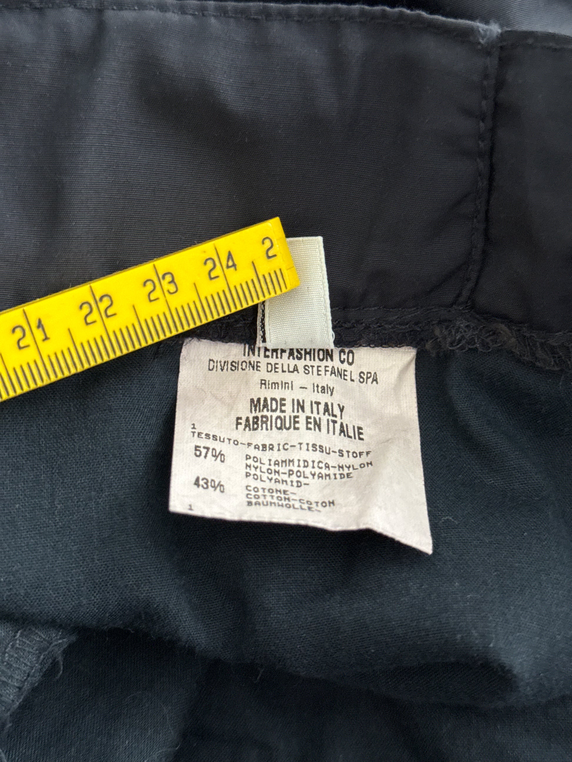 Clothing label on a dark fabric with a yellow ruler for scale
