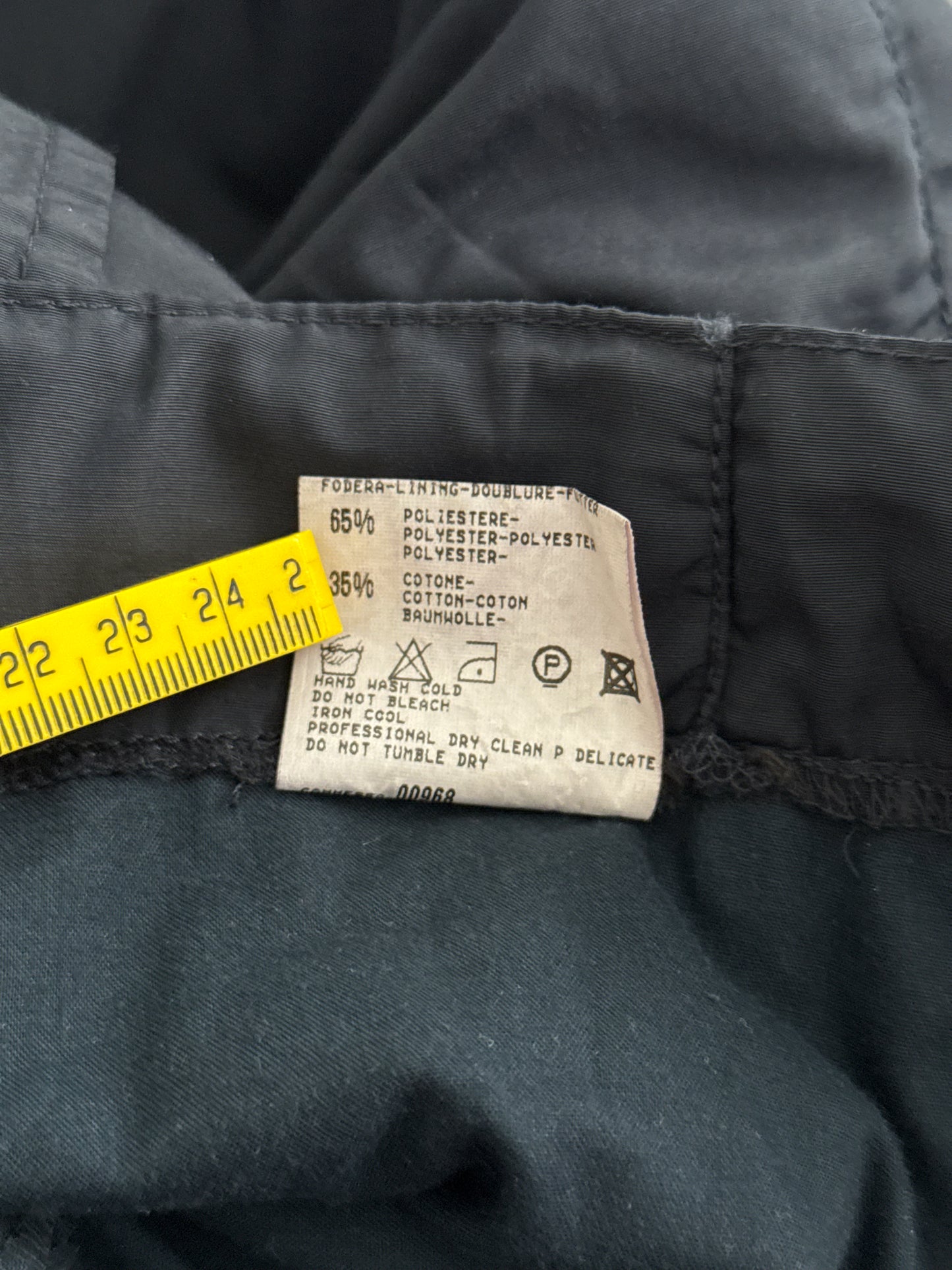 Clothing label with care instructions and measurements on a navy fabric background