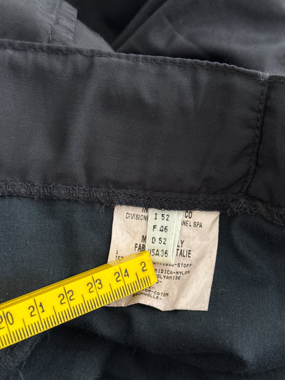 Close-up of a black fabric garment with a label and yellow measuring tape.