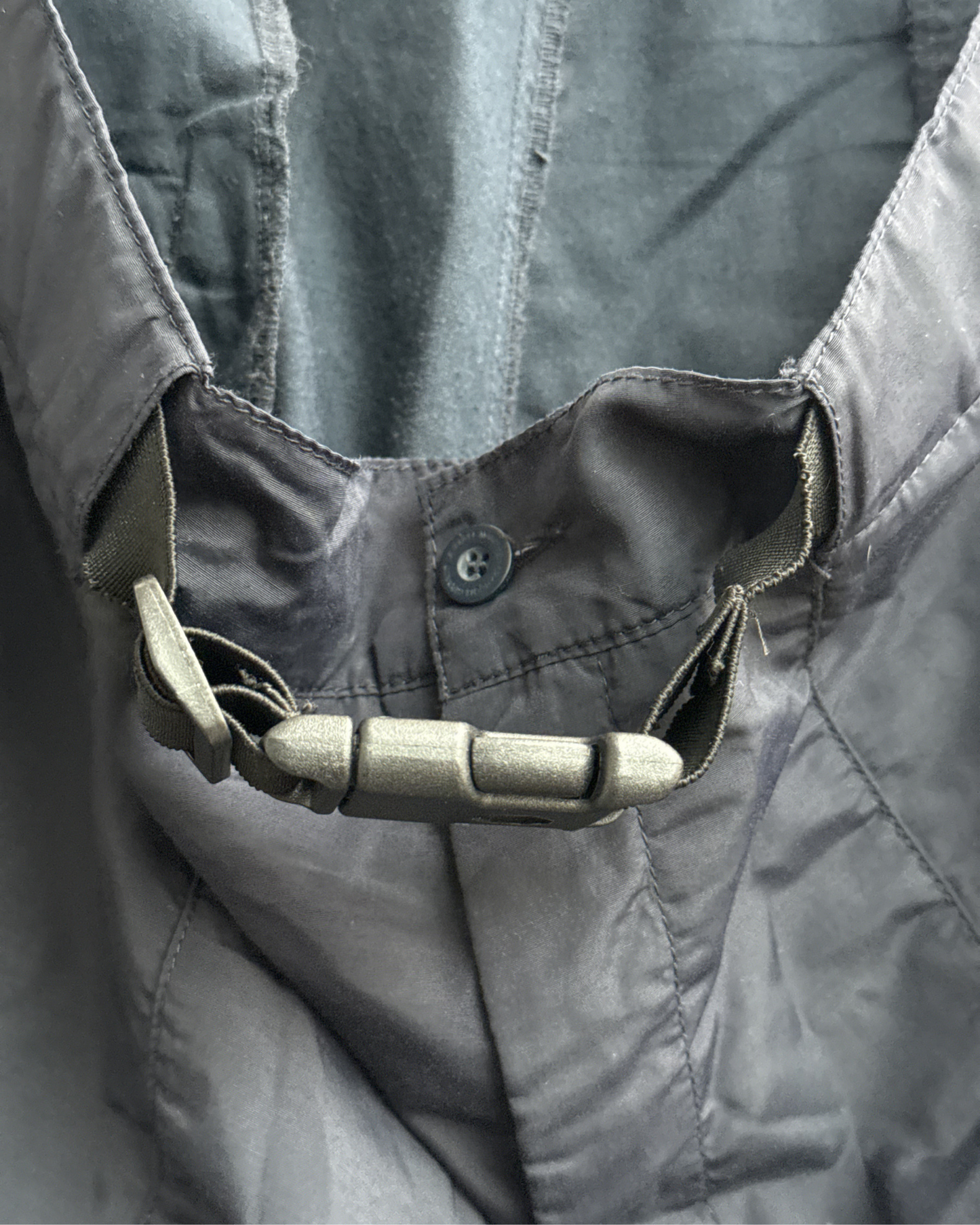Close-up of a navy cargo pants with a zipper, button and tactical clip details