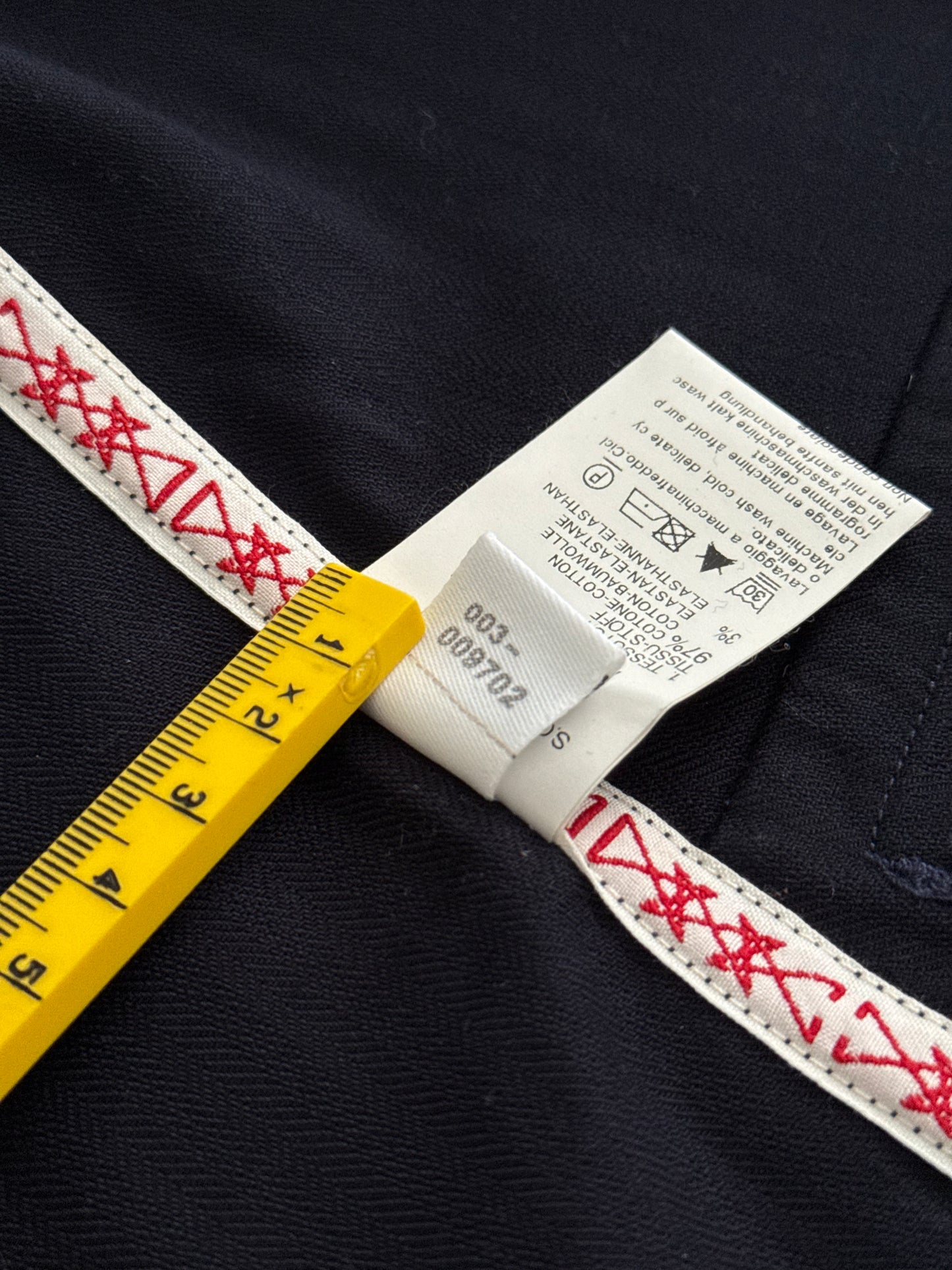 Close-up of a label on a garment with a yellow ruler for scale.