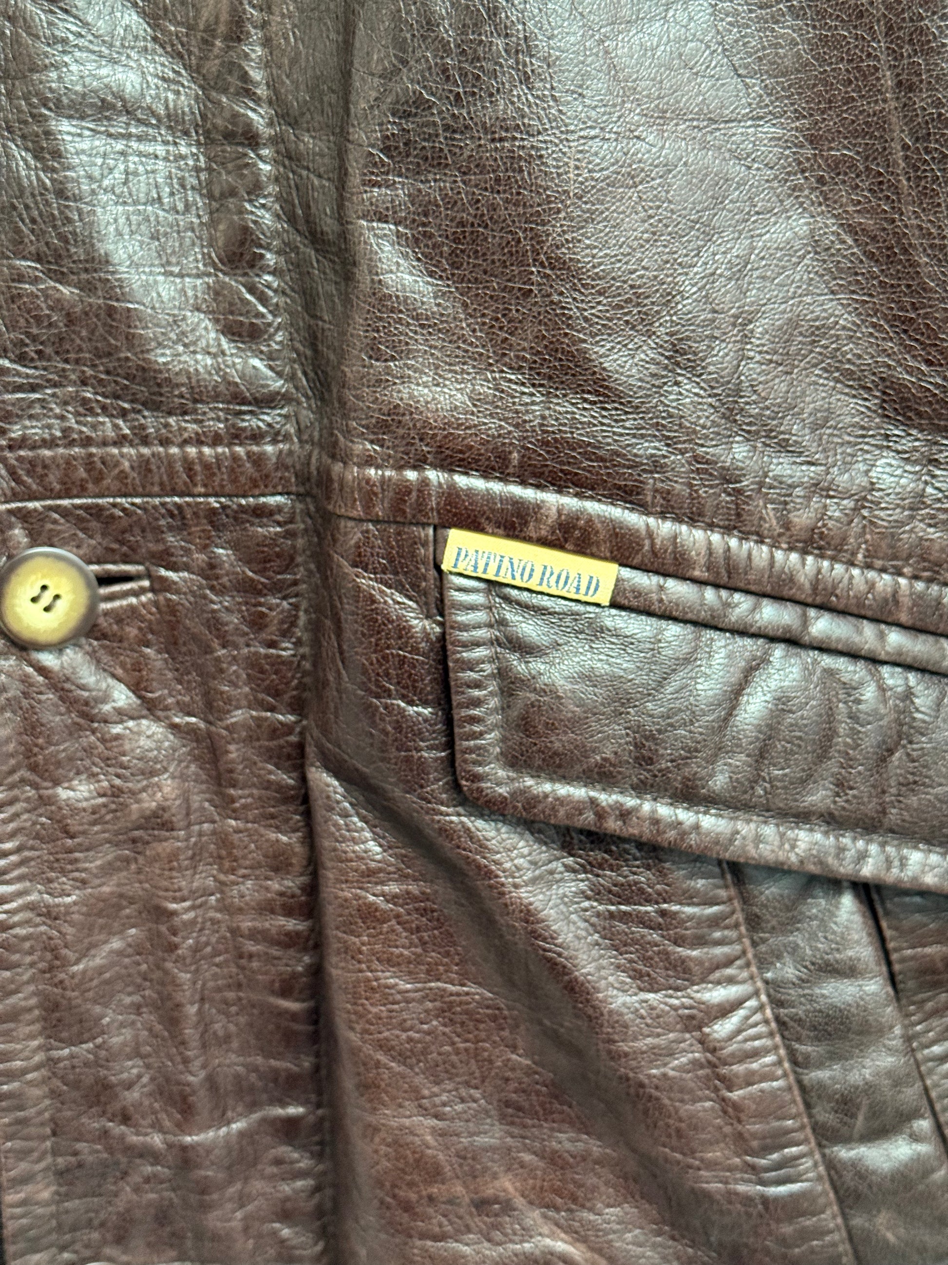 Close up of cowhide leather texture and patino logo on Patino Road vintage overcoat