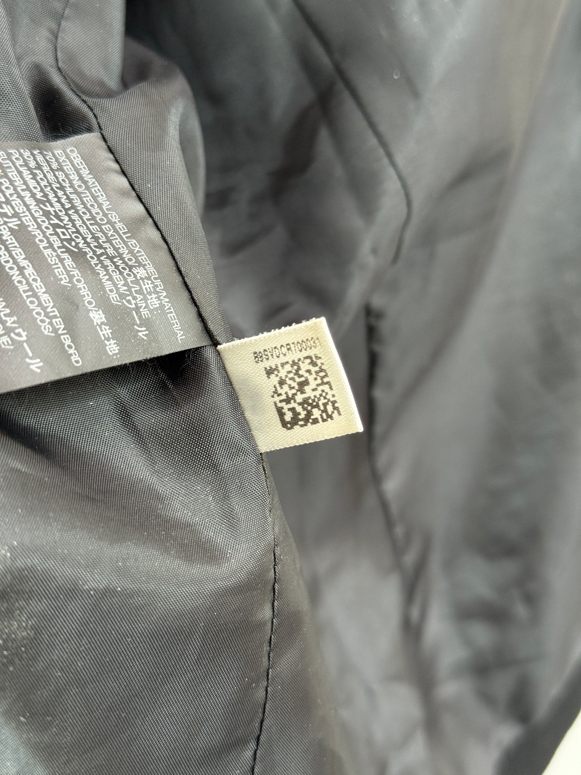 Close-up of a black jacket with a label featuring a QR code on a dark background