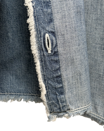 Close-up of a denim fabric with frayed edge and button hole