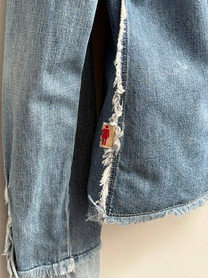 Close-up of a denim jacket with a brand tag on a neutral background